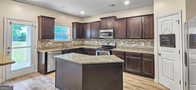 kitchen with stainless steel appliances, a center island, light hardwood / wood-style flooring, and plenty of natural light