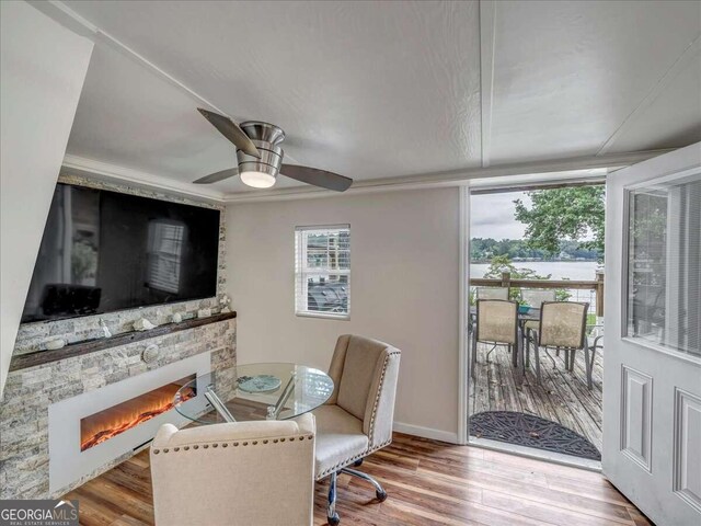 dining room with a stone fireplace, ceiling fan, and wood-type flooring