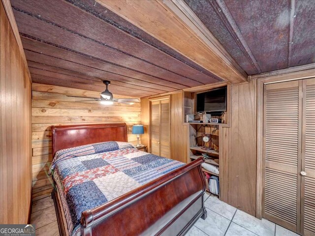 bedroom with tile floors, wood ceiling, ceiling fan, and wood walls