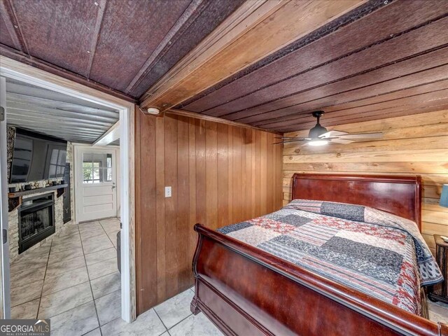 bedroom featuring wooden walls, ceiling fan, wooden ceiling, and light tile floors