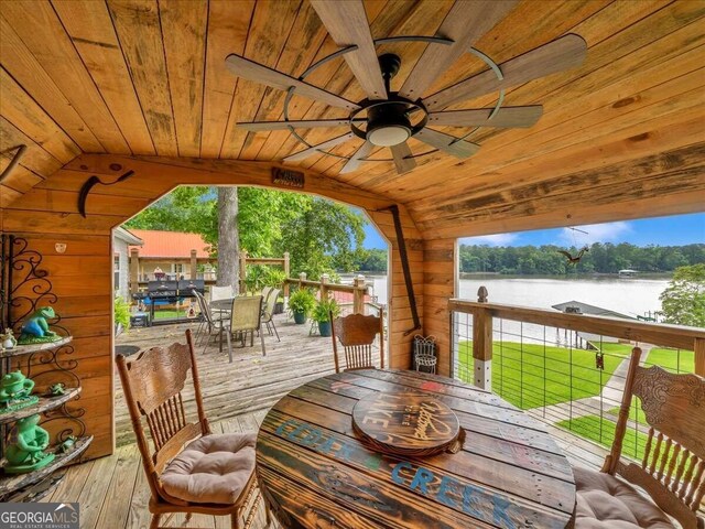 wooden deck featuring ceiling fan, a water view, and a yard