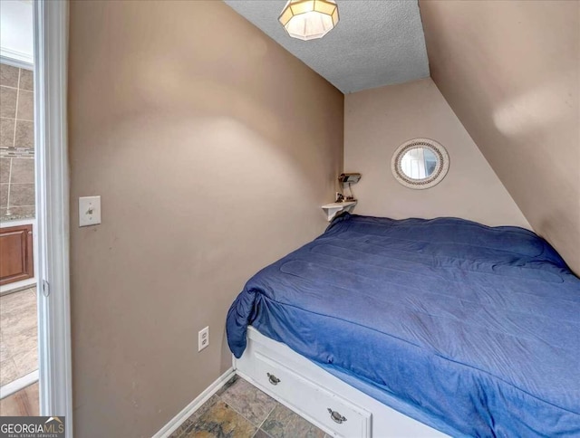 bedroom with tile flooring, vaulted ceiling, and a textured ceiling