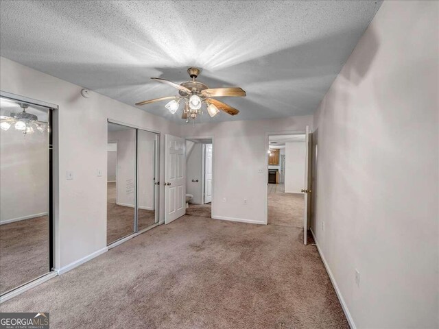 unfurnished bedroom featuring a textured ceiling, carpet flooring, and ceiling fan