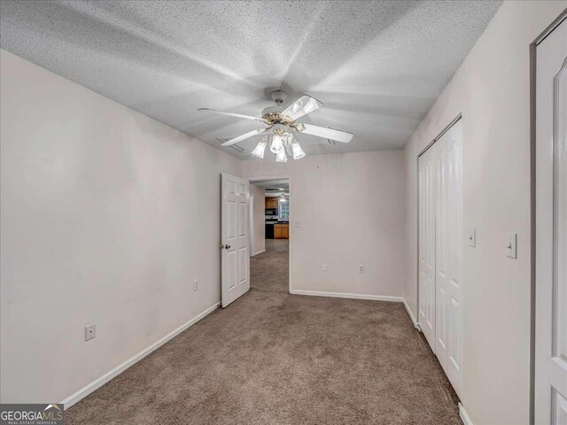 unfurnished bedroom featuring carpet, ceiling fan, and a textured ceiling