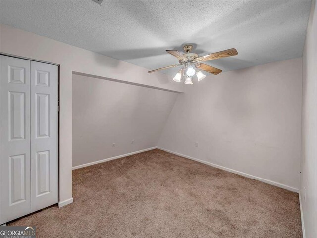 unfurnished bedroom featuring a textured ceiling, lofted ceiling, carpet, and ceiling fan