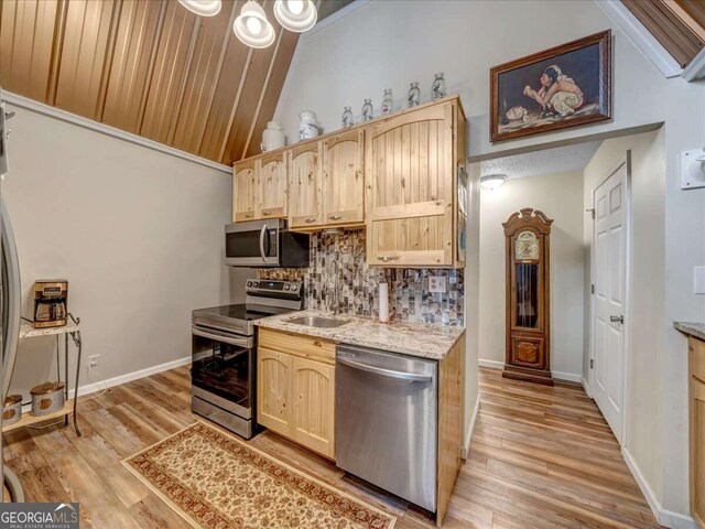 kitchen featuring appliances with stainless steel finishes, tasteful backsplash, light wood-type flooring, and light brown cabinetry