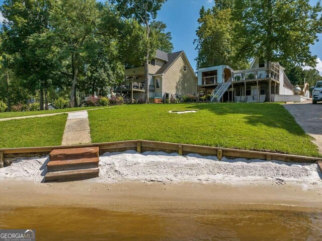 back of property with a lawn and a water view