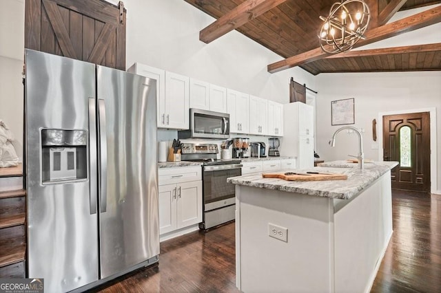 kitchen with stainless steel appliances, wooden ceiling, white cabinets, and a barn door