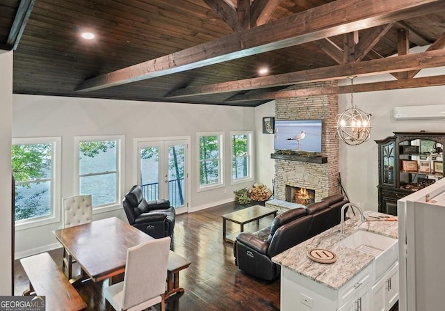 living room with dark wood-style floors, a wall mounted air conditioner, vaulted ceiling with beams, and a stone fireplace