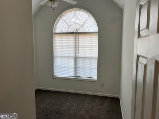 empty room with dark colored carpet, vaulted ceiling, and ceiling fan