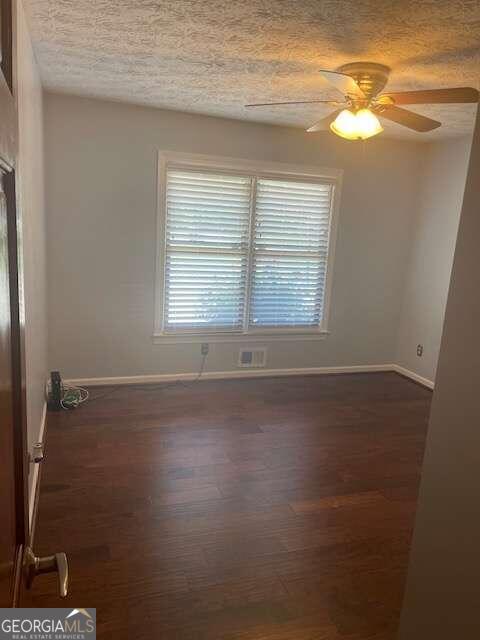 spare room featuring a wealth of natural light, dark hardwood / wood-style floors, and ceiling fan