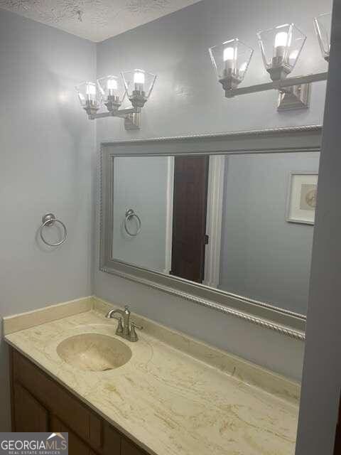 bathroom featuring vanity, a chandelier, and a textured ceiling