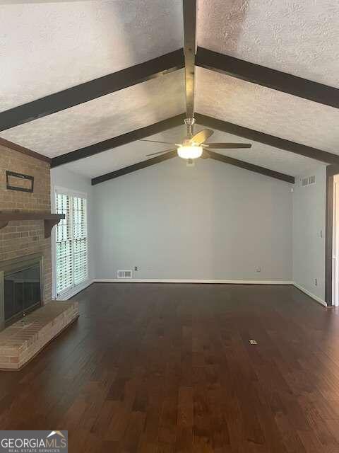 unfurnished living room with dark hardwood / wood-style flooring, vaulted ceiling with beams, a fireplace, and brick wall