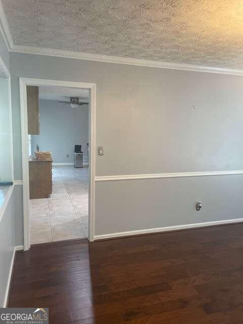 tiled empty room with ceiling fan, ornamental molding, and a textured ceiling