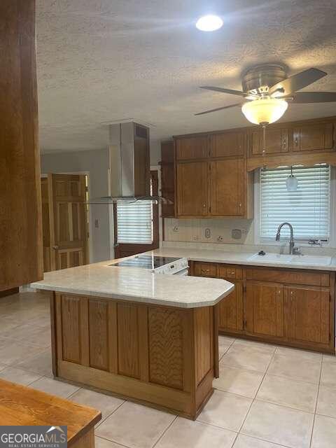 kitchen featuring ceiling fan, light tile flooring, stove, wall chimney range hood, and sink