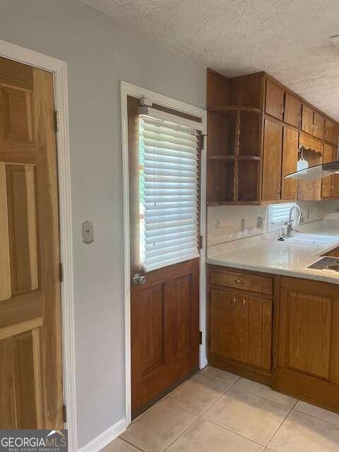 kitchen featuring sink, a textured ceiling, and light tile floors