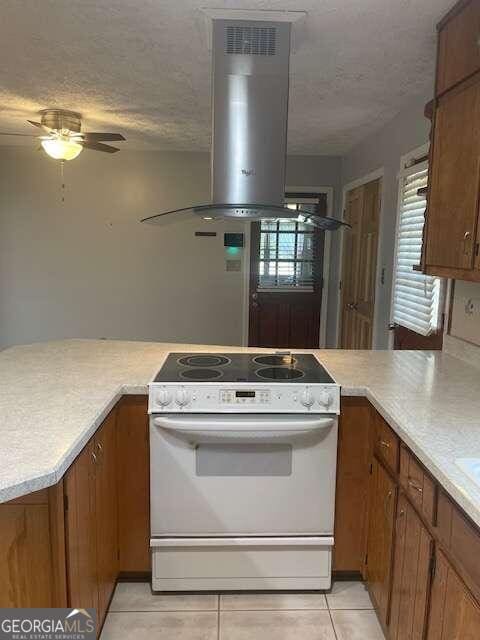 kitchen with light tile floors, white range, ceiling fan, and island range hood