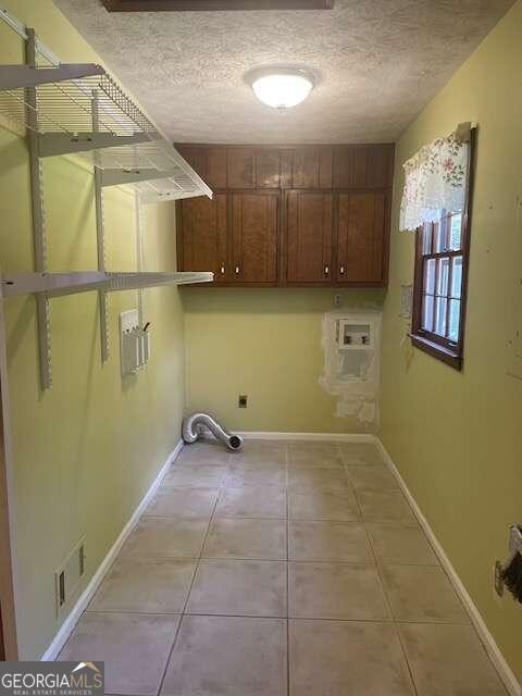 washroom featuring cabinets, tile flooring, washer hookup, and a textured ceiling