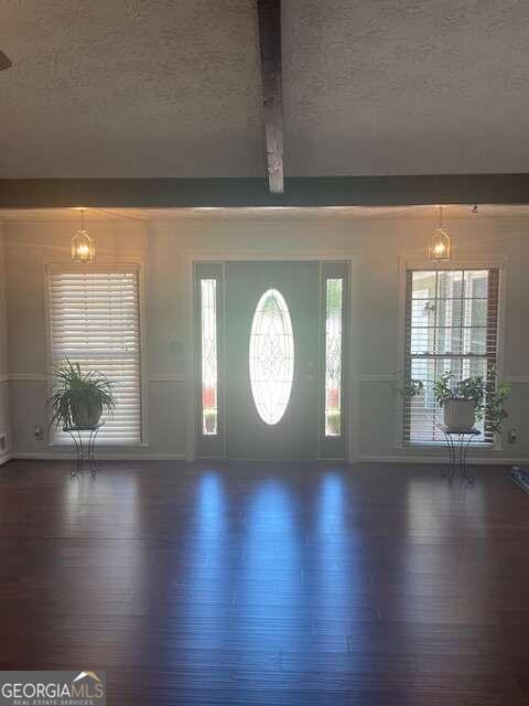 entryway with beamed ceiling, a textured ceiling, and dark hardwood / wood-style floors