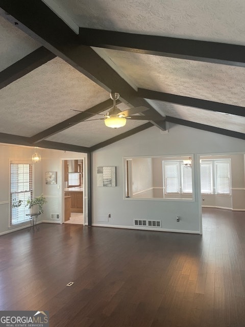 unfurnished living room with dark wood-type flooring, lofted ceiling with beams, and a textured ceiling