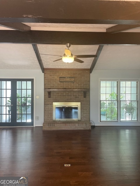 unfurnished living room with beamed ceiling, dark hardwood / wood-style flooring, and plenty of natural light