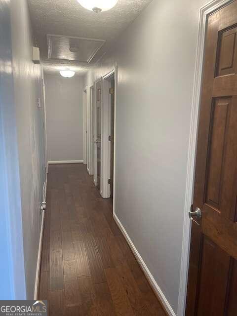 hall with dark hardwood / wood-style flooring and a textured ceiling