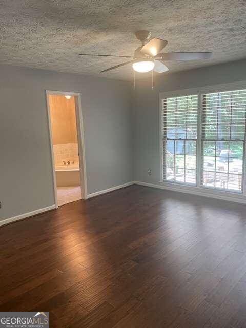 unfurnished room with a textured ceiling, dark hardwood / wood-style floors, and ceiling fan