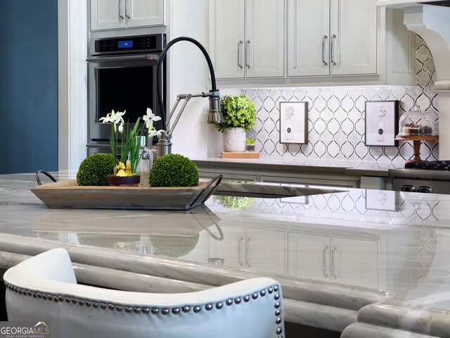 interior space with backsplash, white cabinets, and double oven