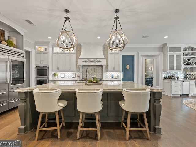 kitchen with premium range hood, tasteful backsplash, and a kitchen island with sink