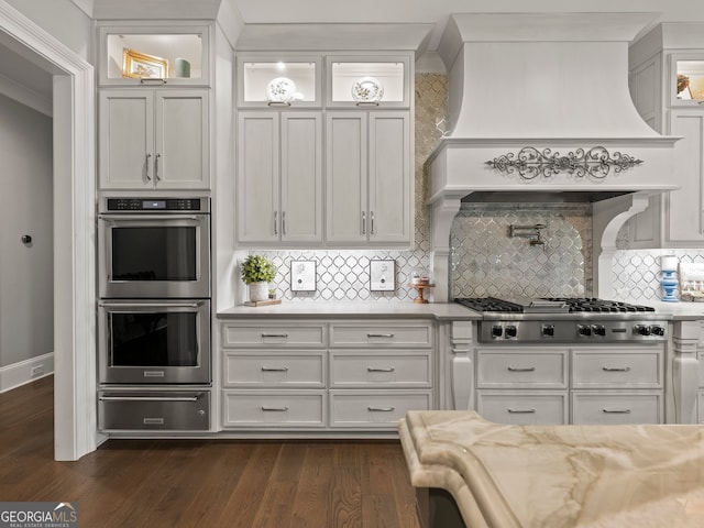 kitchen with appliances with stainless steel finishes, backsplash, dark hardwood / wood-style floors, and custom exhaust hood