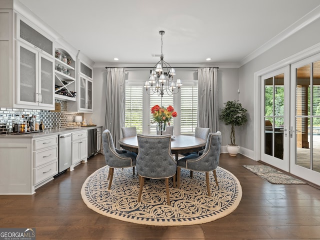 dining space with an inviting chandelier, dark hardwood / wood-style flooring, ornamental molding, and french doors