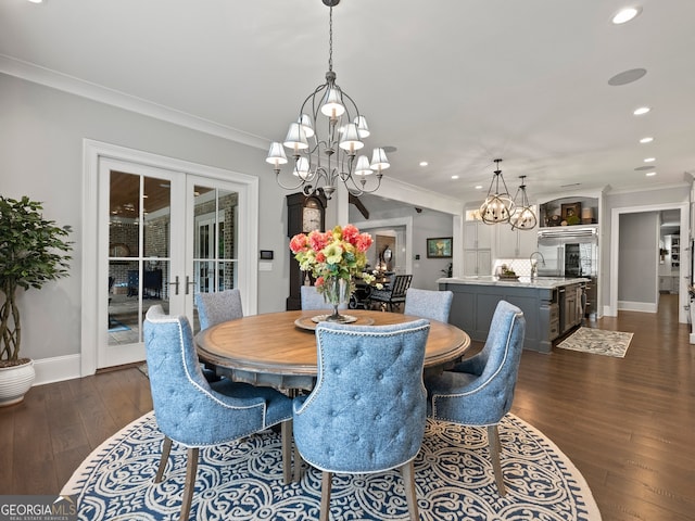 dining space featuring a notable chandelier, ornamental molding, dark wood-type flooring, sink, and french doors