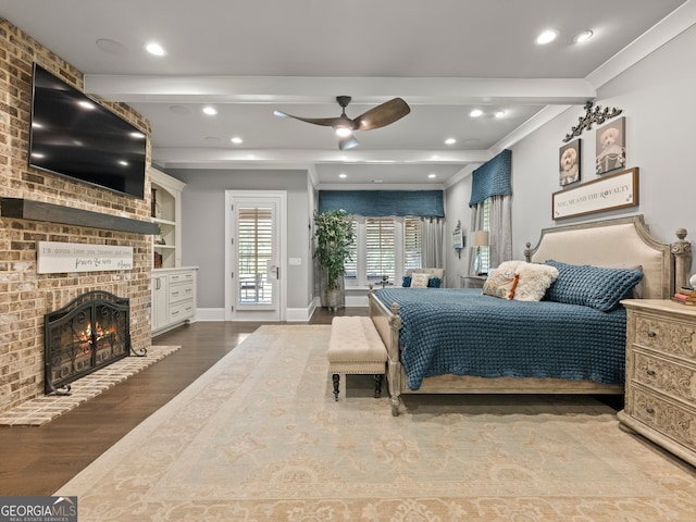 bedroom with beamed ceiling, hardwood / wood-style flooring, a fireplace, and access to exterior