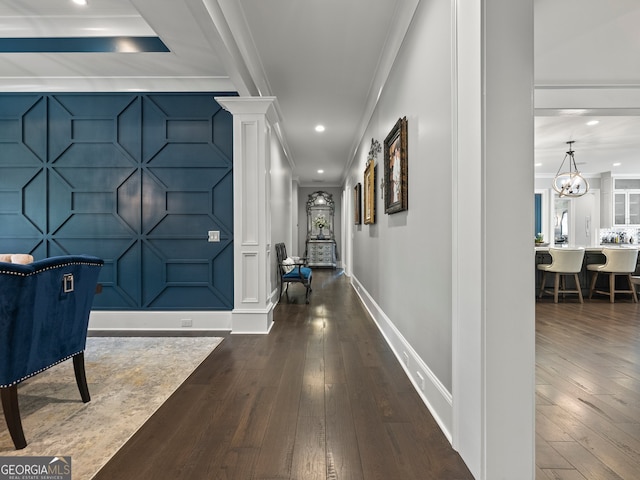 entryway with a notable chandelier, ornamental molding, wood-type flooring, and ornate columns