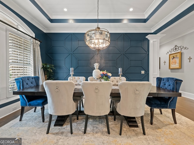 dining room featuring a raised ceiling, a chandelier, light wood-type flooring, and crown molding