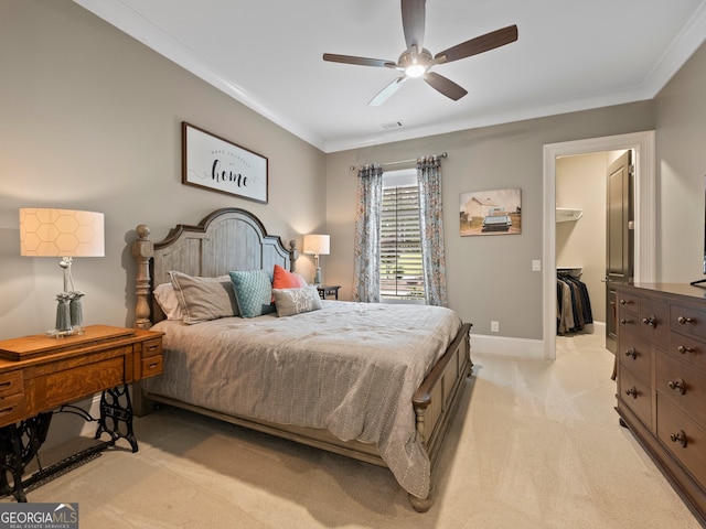 bedroom with ceiling fan, a closet, crown molding, light carpet, and a walk in closet