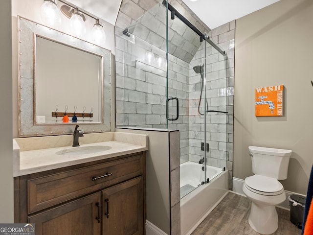 full bathroom featuring shower / bath combination with glass door, vanity with extensive cabinet space, hardwood / wood-style floors, and toilet