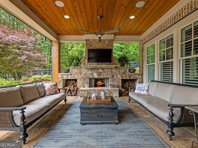 view of patio / terrace with an outdoor living space with a fireplace, ceiling fan, and a deck