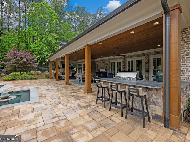 view of terrace featuring an outdoor kitchen, ceiling fan, a grill, and exterior bar