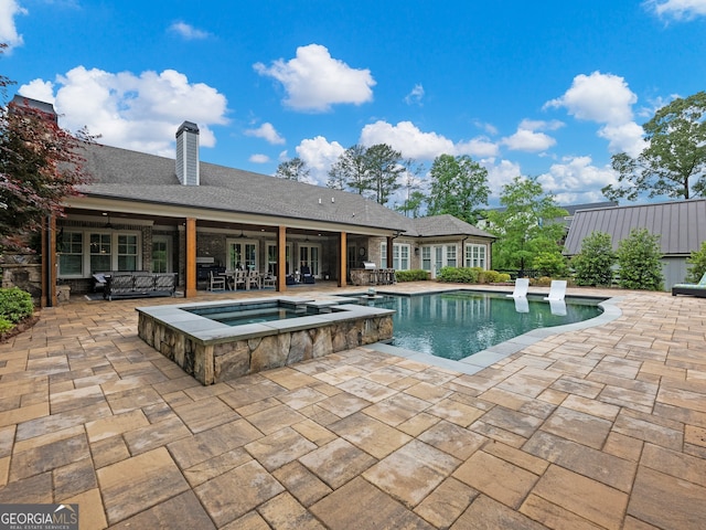 view of swimming pool featuring an in ground hot tub and a patio area