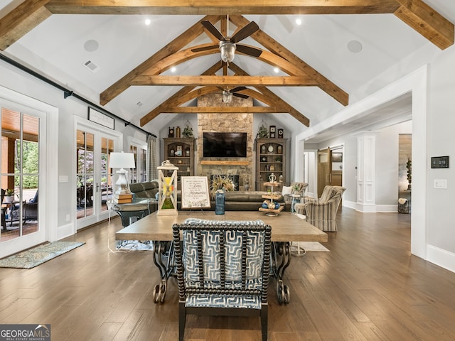 living room featuring wood-type flooring, a stone fireplace, and beam ceiling