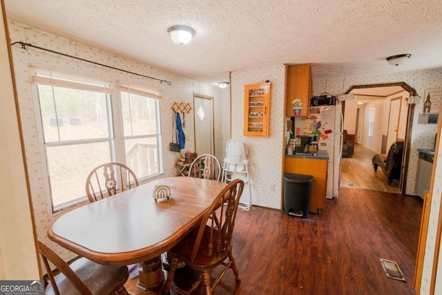 dining space with dark wood-type flooring and a textured ceiling