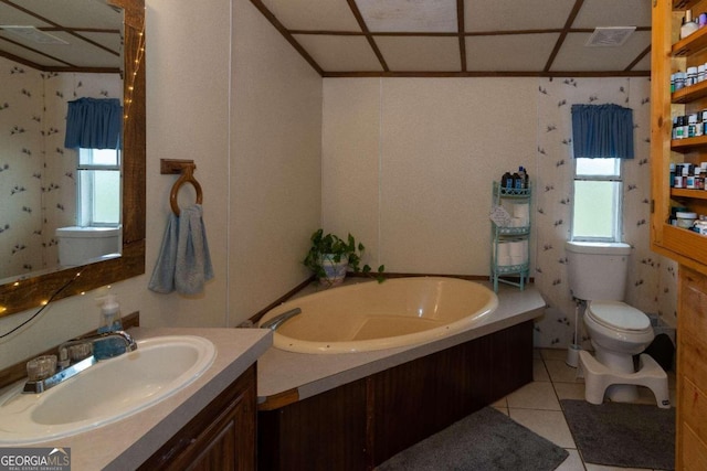 bathroom with tile flooring, a washtub, a drop ceiling, vanity, and toilet