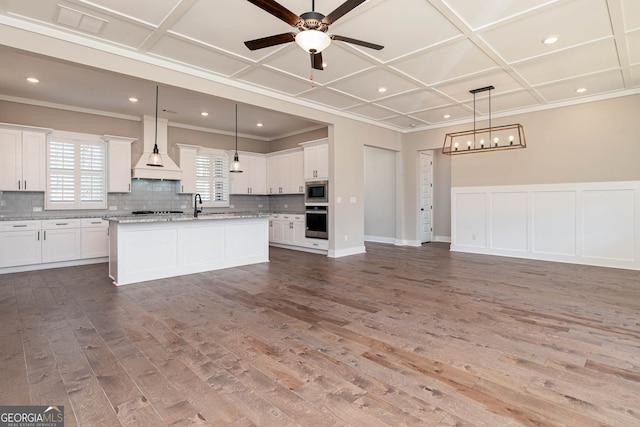 kitchen featuring wood-type flooring, pendant lighting, custom range hood, and stainless steel appliances