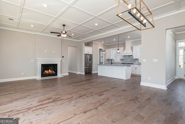 unfurnished living room with coffered ceiling, ceiling fan, sink, and wood-type flooring