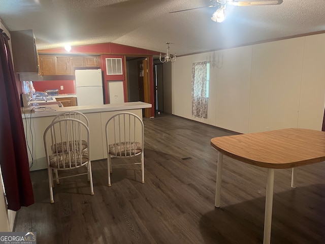 dining room featuring a textured ceiling, wood-type flooring, ceiling fan, and vaulted ceiling