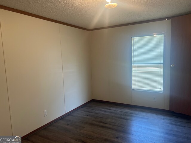 spare room with crown molding, a textured ceiling, and dark hardwood / wood-style floors