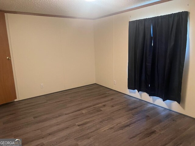 empty room with a textured ceiling and dark wood-type flooring