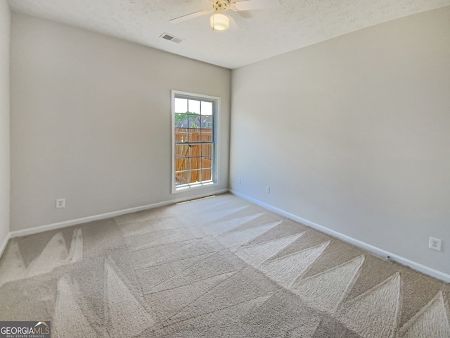 unfurnished room with ceiling fan, a textured ceiling, and carpet floors