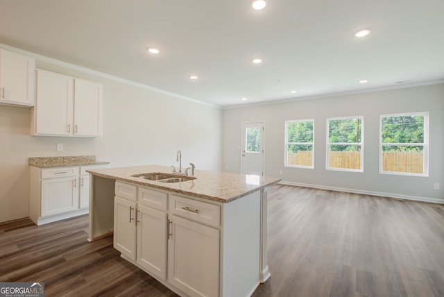 kitchen with a kitchen island with sink, sink, and white cabinetry